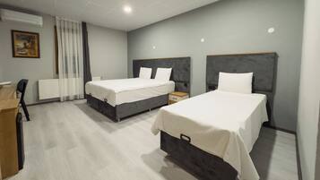 Habitación de hotel con dos camas, un escritorio y una silla.