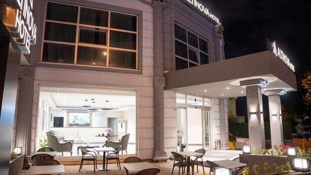 A modern hotel exterior with a well-lit entrance, outdoor seating area, and a visible restaurant inside. - Altınova Hotel Sakarya  (Serdivan)