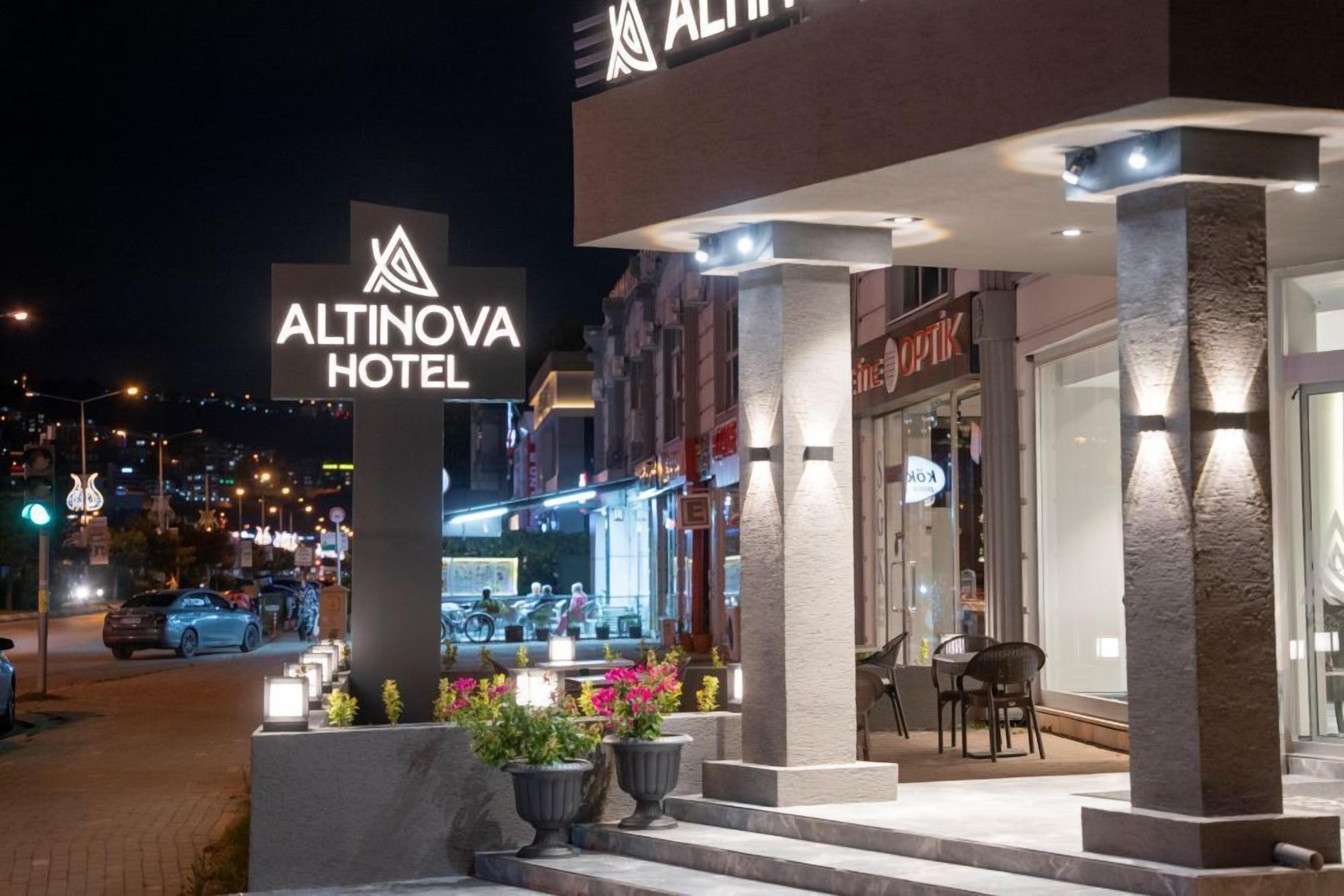 The exterior of the Altinova Hotel with a prominent sign, outdoor seating area, and a view of the street at night.