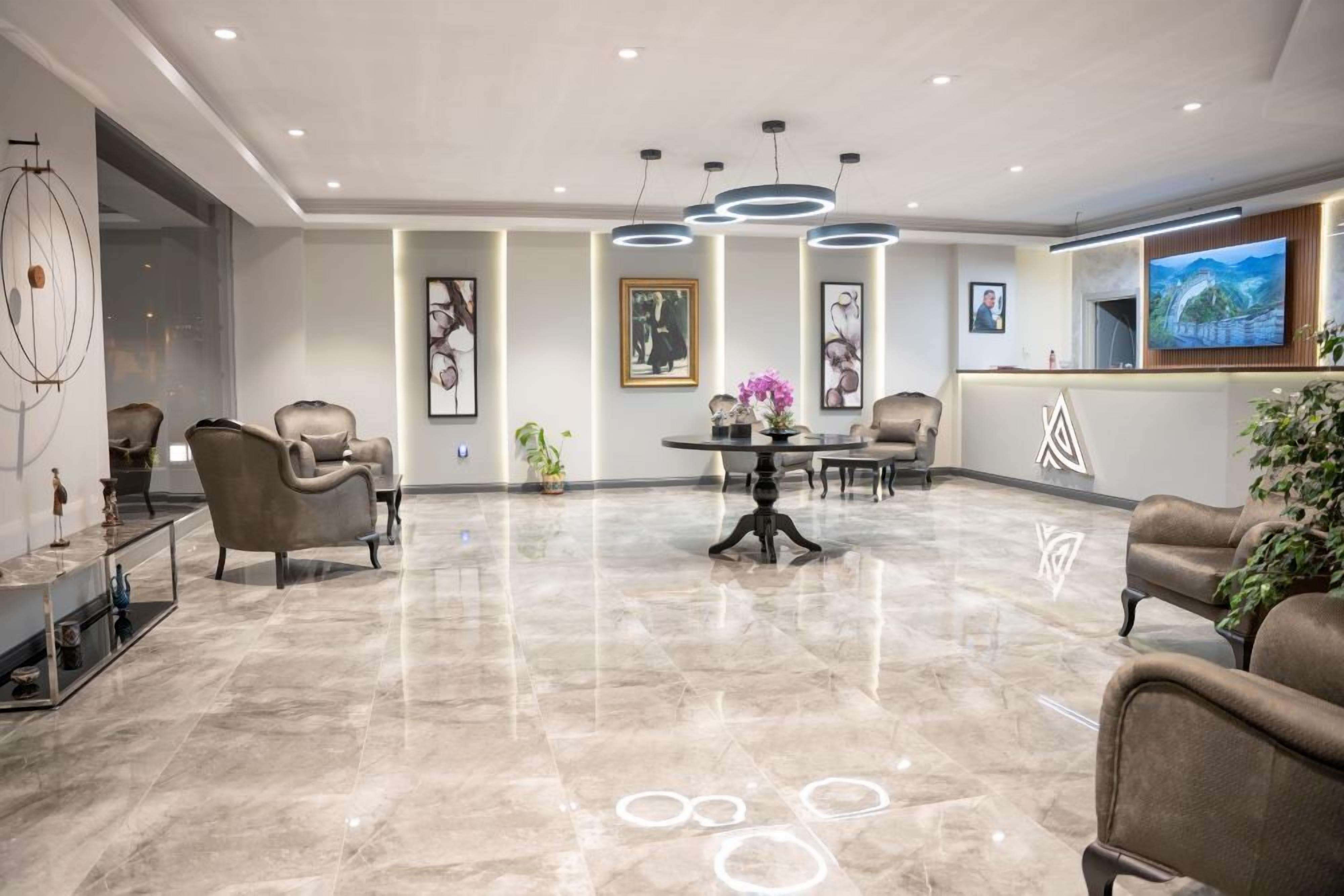 Een moderne hotel lobby met een marmeren vloer, een zithoek en een receptiebalie.