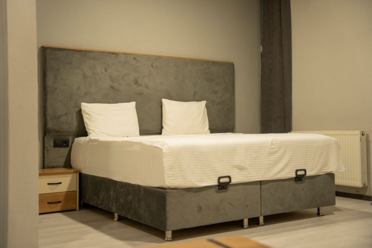 A bedroom with a bed, a nightstand, and a radiator.