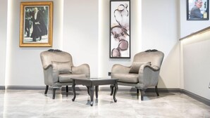 A modern lobby with two armchairs, a coffee table, and abstract art on the walls. - Altınova Hotel Sakarya  (Serdivan)