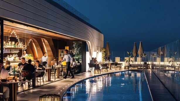 Un espace aménagé au bord de la piscine, comprenant un bar et un coin repas, ainsi qu’une piscine et une façade de bâtiment au design moderne.