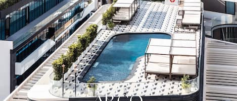 A rooftop pool with lounge chairs and a sign for ARCO COLLEGE.