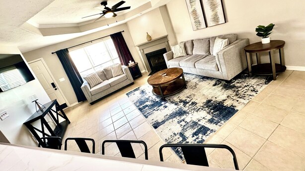 A spacious living room with a fireplace, a sofa, a coffee table, and a dining area with chairs. - The Tiled Waters Retreat (Brandon)