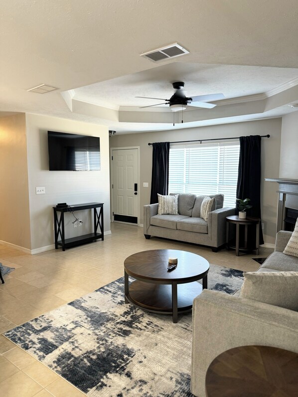 A living room with a sofa, coffee table, and a TV mounted on the wall.