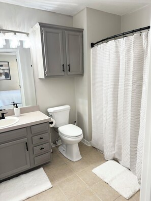 A bathroom with a toilet, sink, and cabinet.