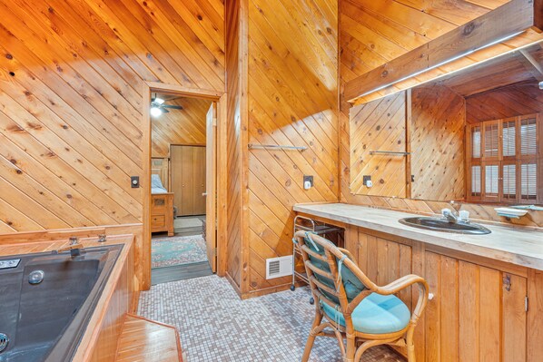 A wooden cabin interior with a bathroom, a sink, a chair, and a bathtub.