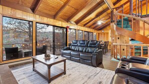 A spacious living area with a leather sofa, a wooden coffee table, and a staircase with a rope handrail.