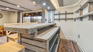 A modern kitchen with a wooden table, built-in shelves, and a large window offering a view of the outdoors.