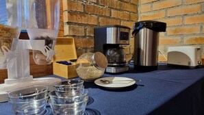 A breakfast setup with a coffee maker, a toaster, and various breakfast items on a table. - Antu Apart Hotel Villarrica (Villarrica)