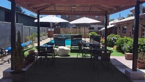 A covered patio area with outdoor seating, a pool, and a clear blue sky. - Antu Apart Hotel Villarrica (Villarrica)