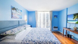 A bedroom with a large bed, a TV, and a window with curtains. - Trendy Studio in the Heart of Honolulu - 21F  (Honolulu)