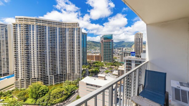 A high-rise building with a balcony overlooking a cityscape, including other tall buildings and a mountain in the background. - Trendy Studio in the Heart of Honolulu - 21F  (Honolulu)