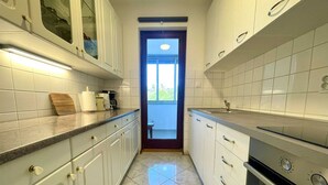 A narrow kitchen with white cabinets, a countertop, and a stove.