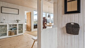 A spacious room with wooden walls and floors, a dining area with a table and chairs, and a view through an open door. - Gorgeous home in Juelsminde with WiFi (Juelsminde)