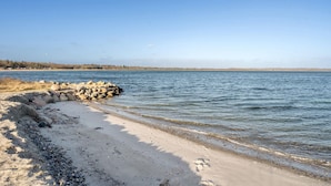 A sandy beach with a rocky breakwater and calm water. - Gorgeous home in Juelsminde with WiFi (Juelsminde)