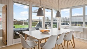 A dining area with a white table and chairs, large windows, and hanging pendant lights. - Gorgeous home in Juelsminde with WiFi (Juelsminde)