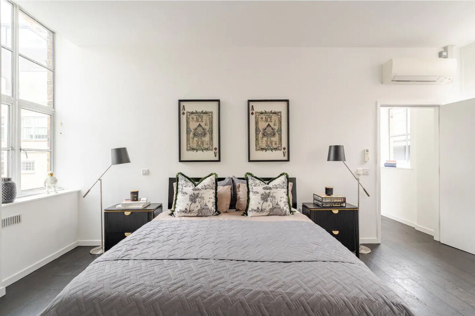 Een slaapkamer met een groot bed, twee nachtkastjes, een raam en twee ingelijste foto's aan de muur.