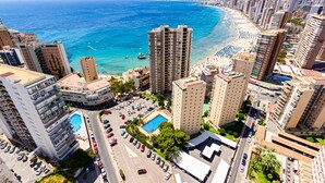 A high-rise hotel with a pool, beach view, and urban surroundings.