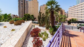 A hotel with multiple floors, outdoor seating areas, and palm trees.