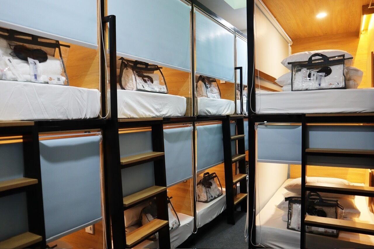 A bunk bed room with multiple beds, each with a pillow and a bag.