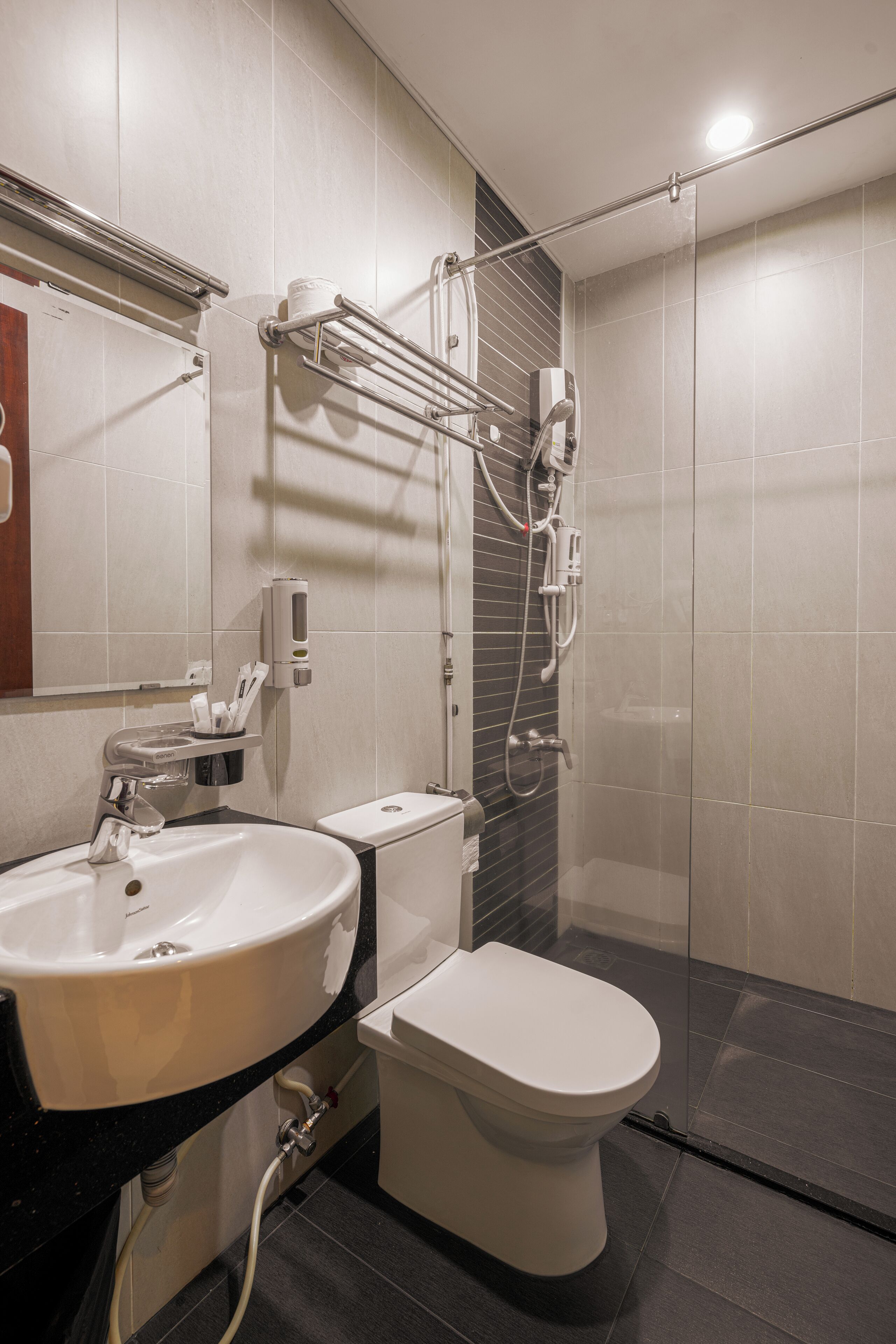 Een moderne badkamer met een wastafel, toilet en douchecabine met glazen wanden.