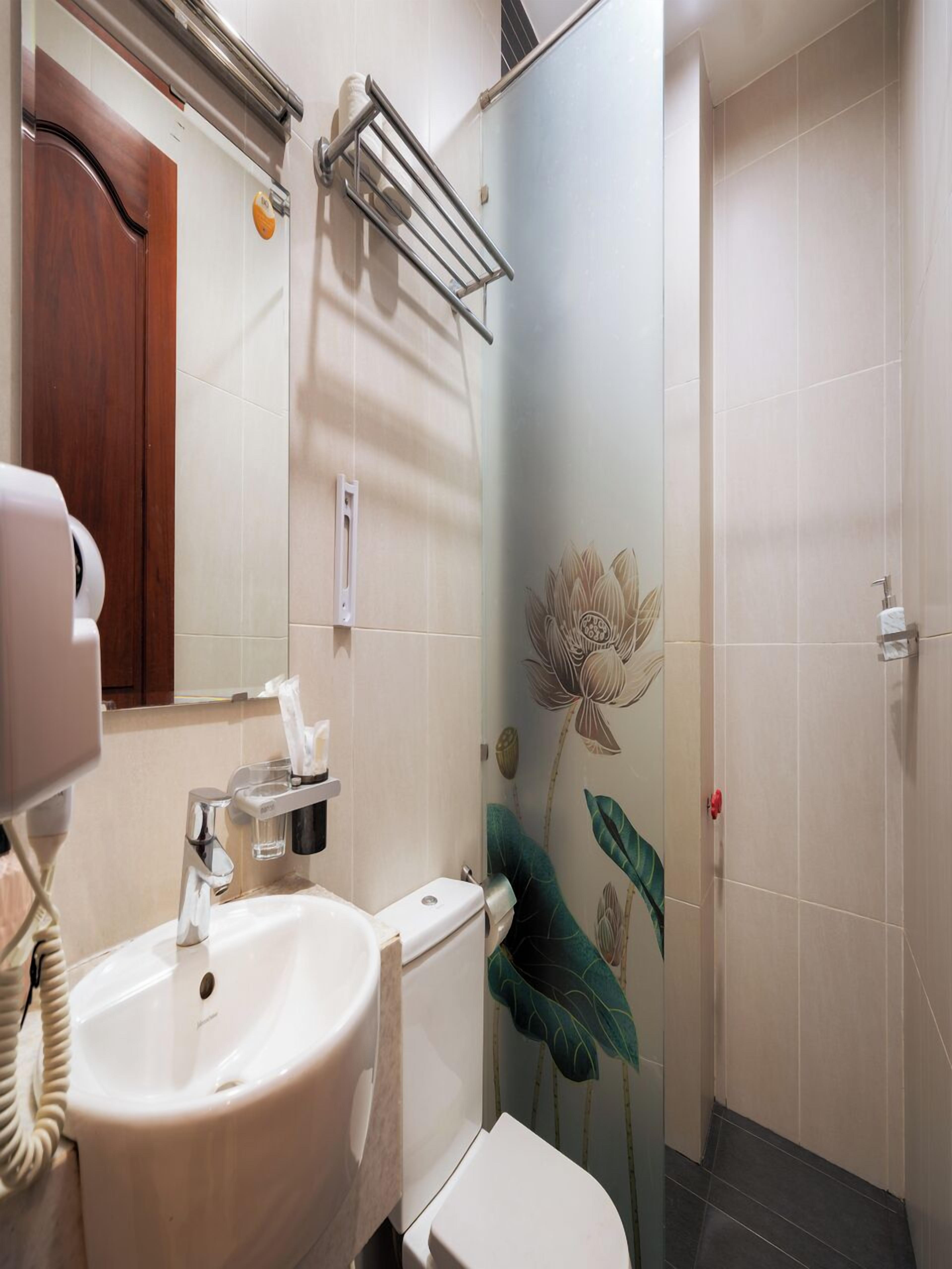 A bathroom with a white sink, a toilet, a towel rack, and a shower area.