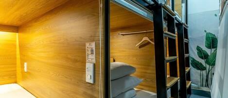 A bunk bed room with wooden walls, a bedside table, and a hanging light fixture.