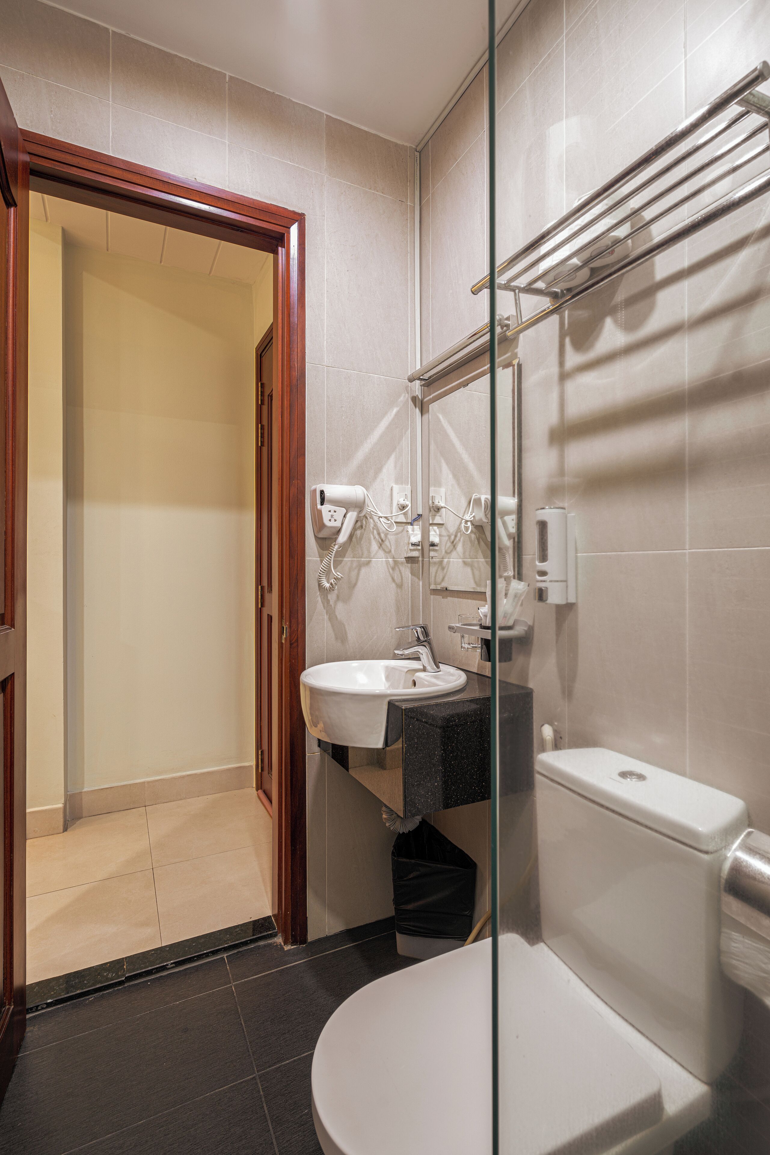 A modern bathroom with a glass partition, a sink, a toilet, and a hairdryer.
