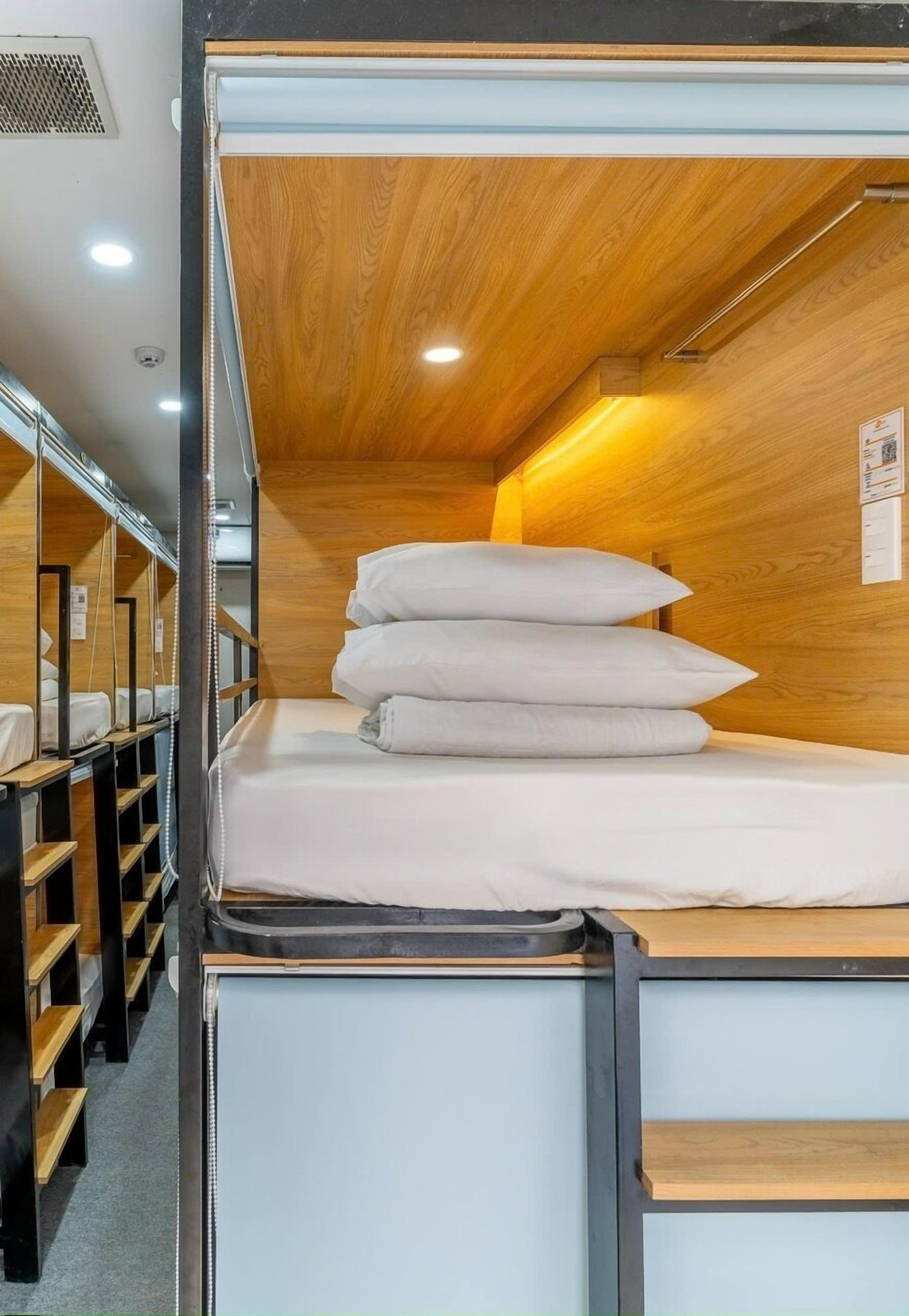 A compact, well-lit room with a bunk bed, wooden panel walls, and a small desk area.