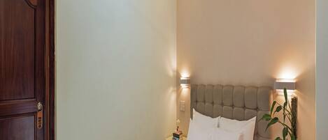 A hotel room with a bed, a nightstand with a lamp, a ceiling fan, and a door.