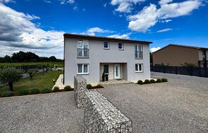 A two-story house with a stone staircase leading to the entrance, surrounded by a gravel driveway and a fenced garden area. - Amazing home in Nedescina (Nedescina)