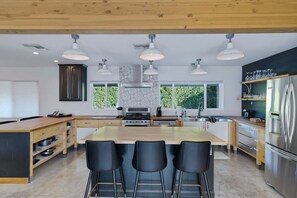 A modern kitchen with a central island, bar stools, and a stainless steel refrigerator. - Playhouse Pool, Pickleball, Basketball, Axe Throwi (Chandler)