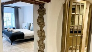 Un dormitorio con un pilar de piedra, una cama y una puerta de madera.