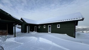 Un edificio cubierto de nieve con techo inclinado, entrada cubierta y cielo despejado.