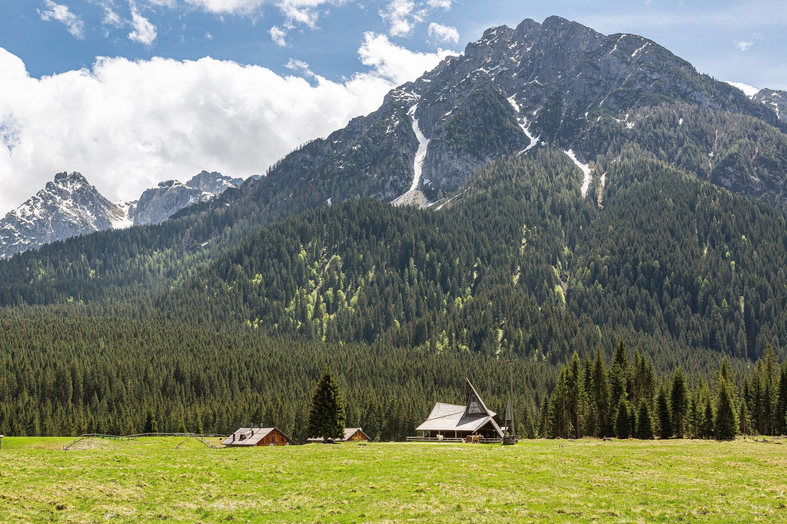 Eine Berglandschaft mit einer Hütte und einem Feld.