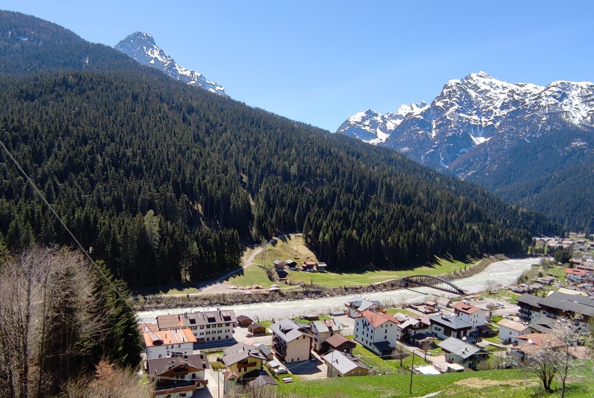 Un pueblo de montaña con casas, un río y picos nevados.