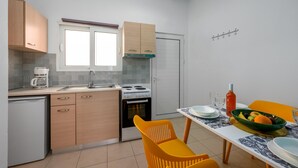 Une cuisine compacte avec un coin repas, comprenant un évier, une cuisinière et des placards.