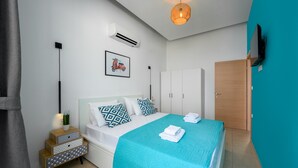 Une chambre à coucher comprenant un lit, une table de chevet, un appareil de climatisation et un téléviseur fixé au mur.
