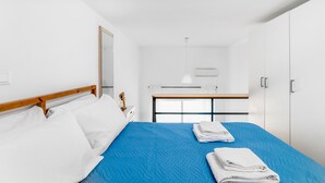 Quarto de hotel com cama, mesa de cabeceira, espelho, guarda-roupa e janela.
