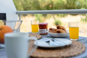 A breakfast table with croissants, a jar of jam, glasses of orange juice, and a white mug. - Studio Apartment 'Sea Front  In Ixia' with Private Garden, Wi-Fi and Air Conditioning (?a??s??)
