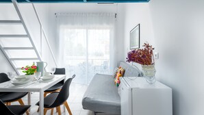 Quarto moderno com uma mesa de jantar, cadeiras, sofá, radiador, janela com cortinas e teto com painéis azuis.