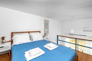 Moderni hotellihuone, jossa on suuri sänky, yöpöytä, peili, näköalalla varustettu ikkuna ja parveke.