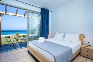 Een slaapkamer met een grote schuifpui die uitkomt op een balkon met uitzicht op zee.