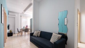 A modern living room with a sofa, a dining table, and a wall-mounted abstract art piece. - Apartment 'Rhodes Sea Ialysos' with Balcony, Wi-Fi and Air Conditioning (Ialisos)