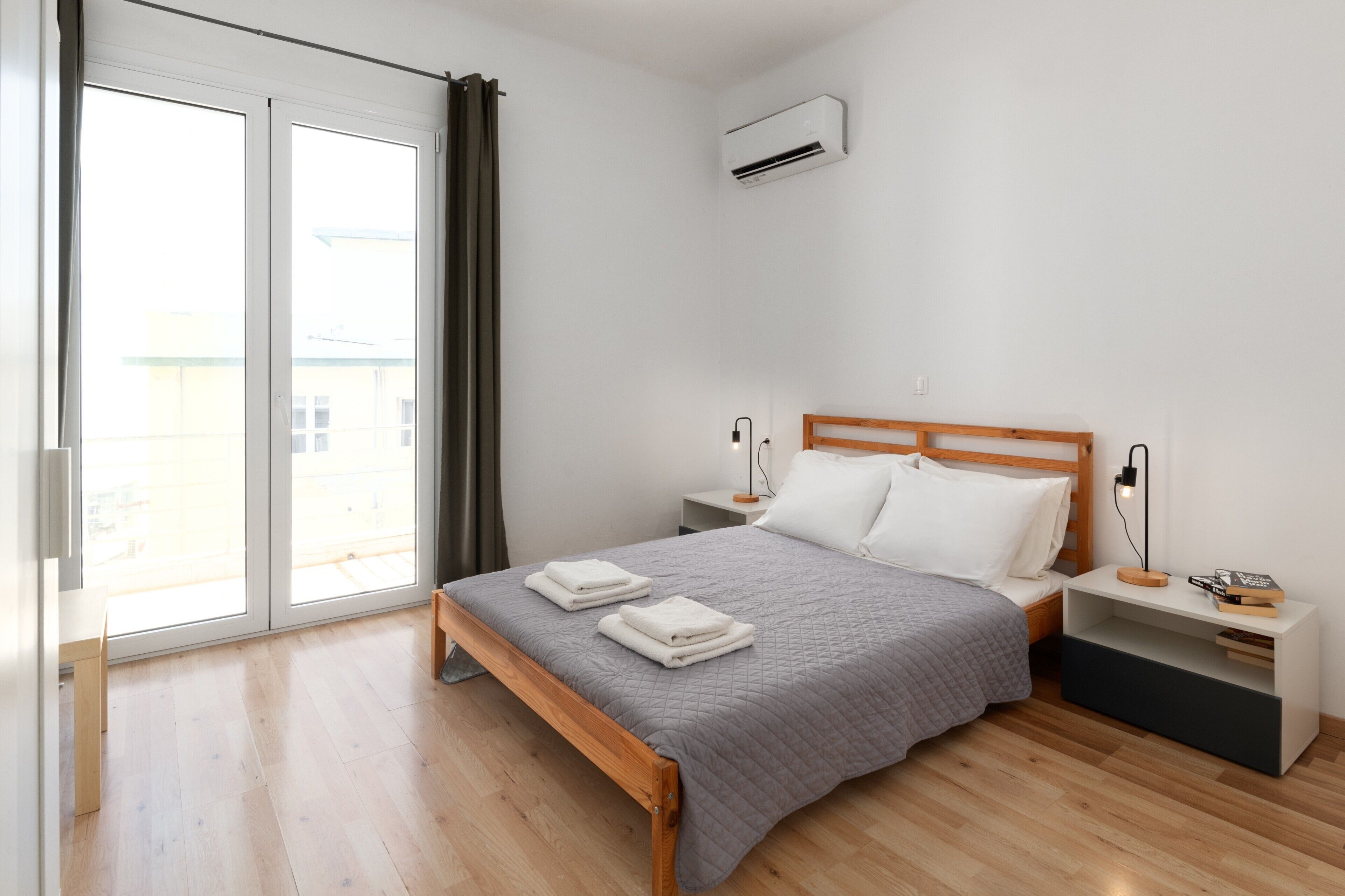 Een slaapkamer met een bed, nachtkastjes, een airconditioning en uitzicht door een schuifdeur.