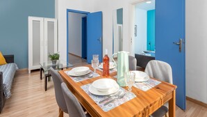Ein Essbereich mit einem Holztisch, gedeckt für vier Personen, einer blauen Tür und einem weißen Kleiderschrank.