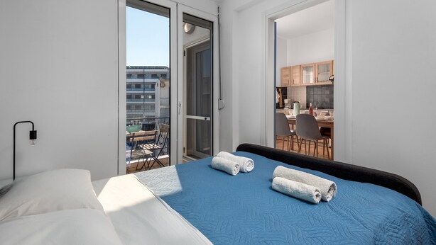 Ein Hotelzimmer mit Bett, einem Balkon mit Blick und einer Küchenzeile.