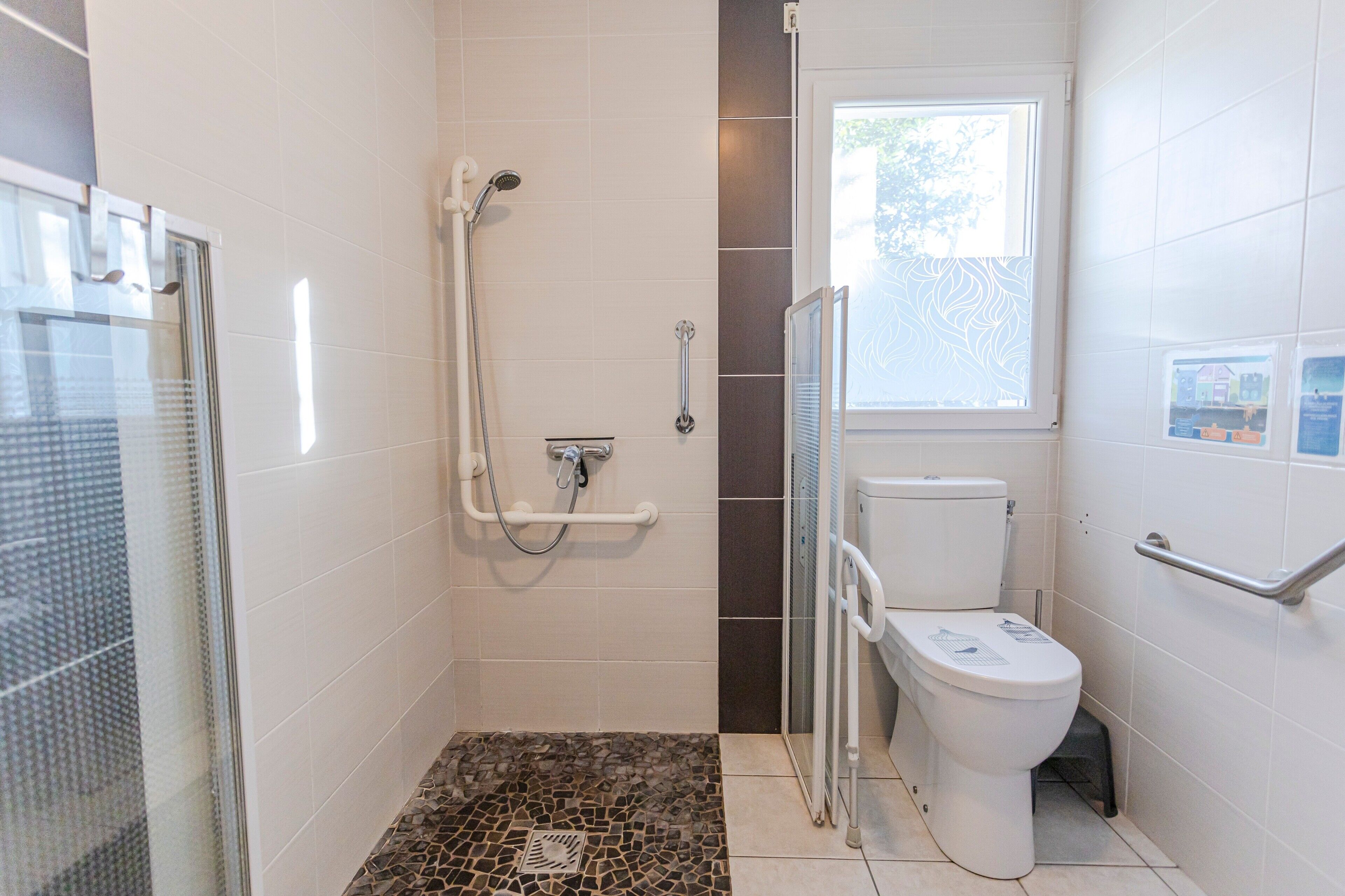 A bathroom with a shower, toilet, and glass door.